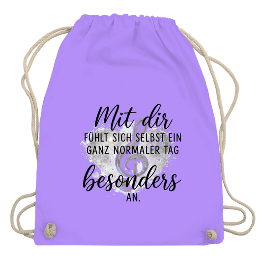 Lavendel-farbiger Turnbeutel aus Baumwolle mit Herz-Motiv, Notenschlüssel und dem Spruch "Mit dir fühlt sich selbst ein ganz normaler Tag besonders an