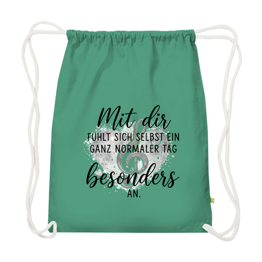 Grüner Premium Bio-Turnbeutel aus schwerer Baumwolle mit Herz-Motiv, Notenschlüssel und dem Spruch "Mit dir fühlt sich selbst ein ganz normaler Tag besonders an"